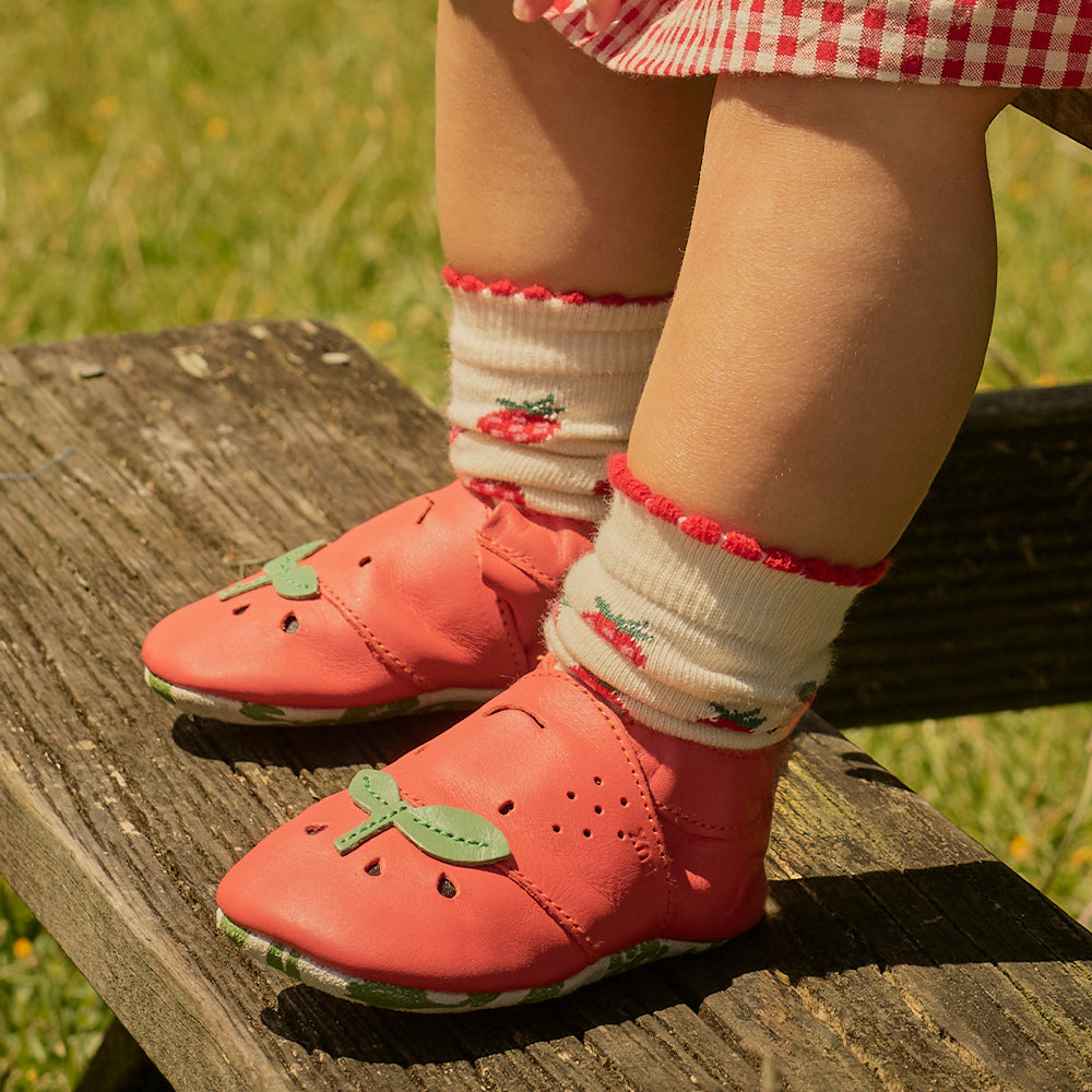 Image of a toddler's feet wearing red tomato design Bobux slip-on shoes